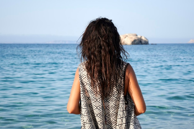 Foto donna in piedi sulla spiaggia ammirando l'orizzonte sull'oceano in una giornata di sole