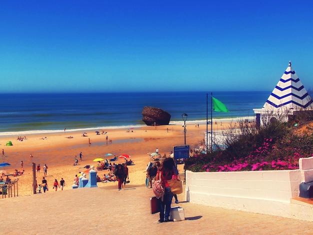 Woman standing at beach against clear blue sky