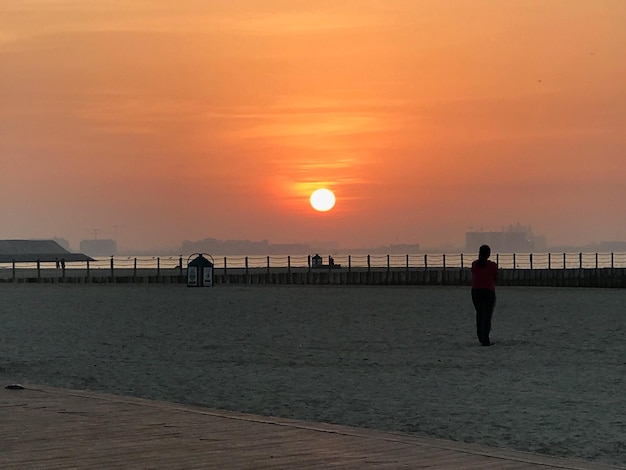 Foto donna in piedi sulla spiaggia contro il cielo durante il tramonto