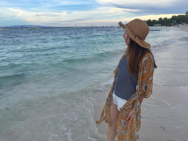 Woman standing at beach against sky