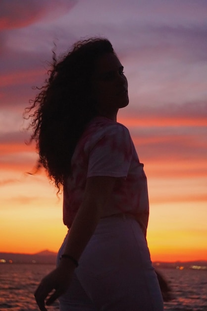 Foto donna in piedi sulla spiaggia durante il tramonto