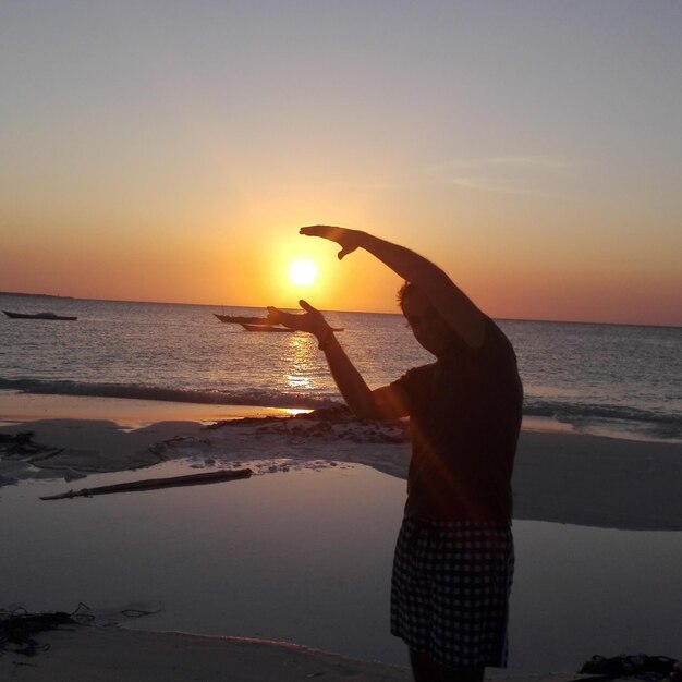 Woman standing at beach during sunset