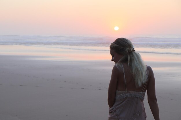 Photo woman standing at beach during sunset