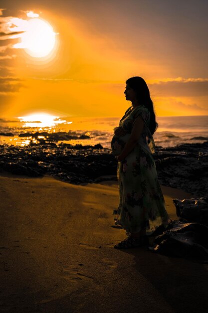 Woman standing at beach during sunset