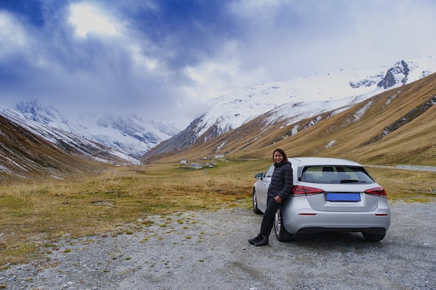 이탈리아 파소 델로 스텔비오(Passo dello Stelvio)의 풍경을 바라보며 차 옆에 서 있는 여성