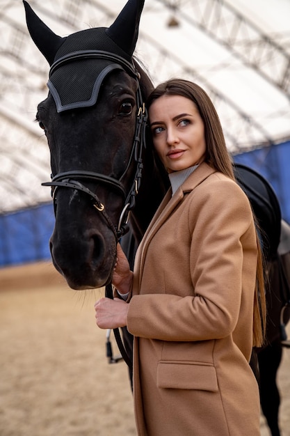 A woman standing next to a black horse