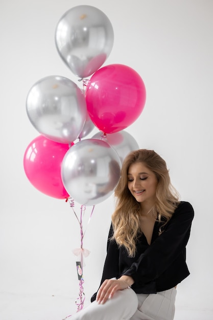 A woman standing next to a bunch of pink and silver balloons