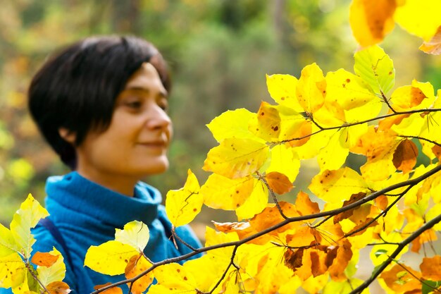 Woman standing by branch in forest during autumn