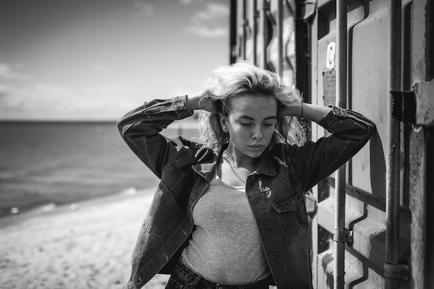 Photo woman standing by cargo container at beach against sky