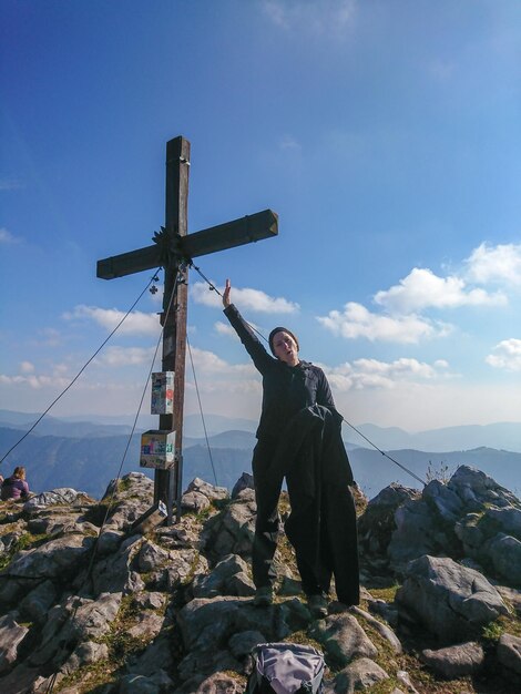 Woman standing by cross on rock