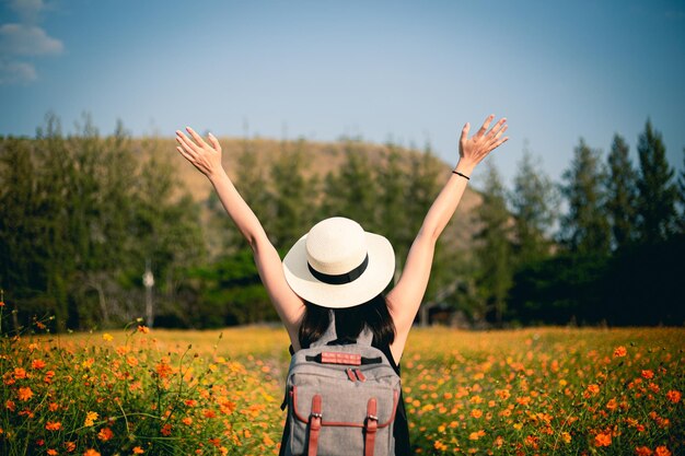 写真 畑で花をかせている植物のそばに立っている女性