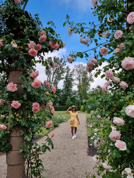 Foto donna in piedi vicino alle piante in fiore