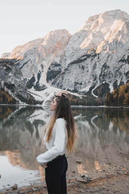 Foto donna in piedi vicino al lago contro le montagne e il cielo