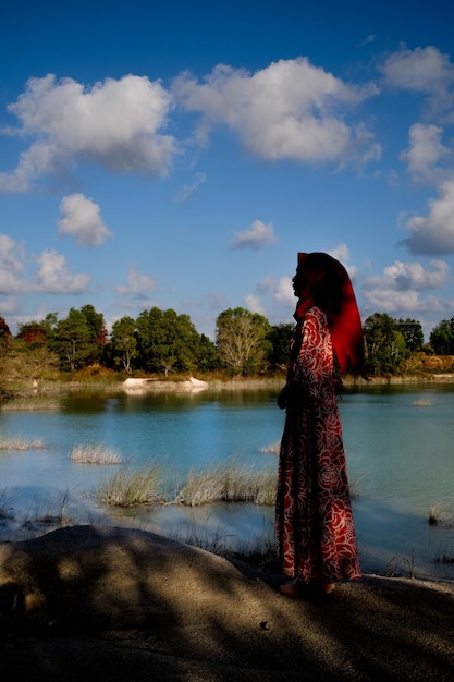 空に向かって湖のそばに立っている女性