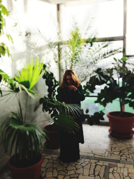 Photo woman standing by potted plants