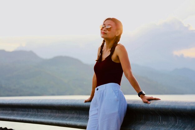 写真 山や空に向かってレールに立っている女性