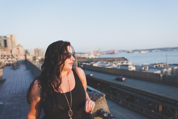 Woman standing by railing against sky