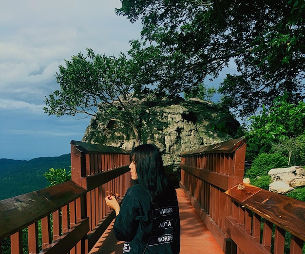 Woman standing by railing on mountain