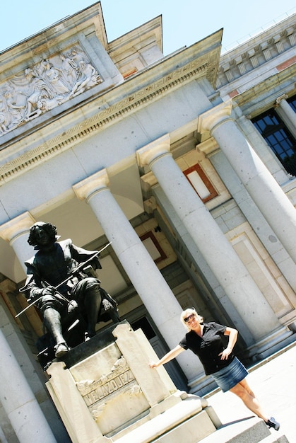 Foto donna in piedi vicino alla statua al museo del prado