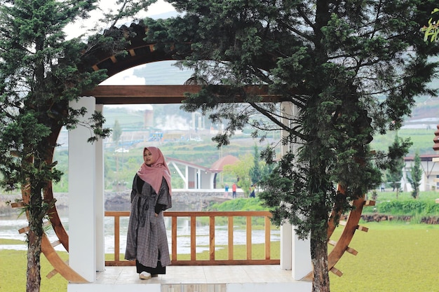 Woman standing by tree against built structure