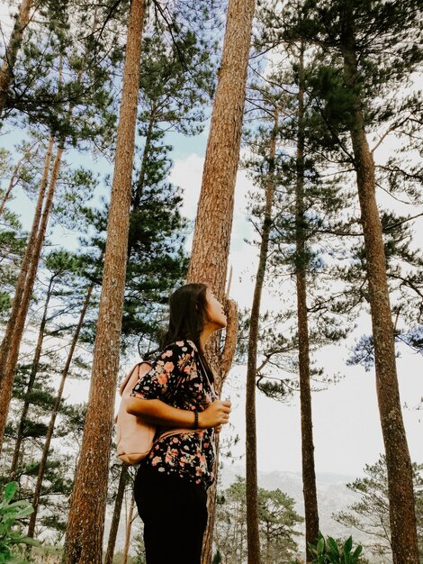 Foto donna in piedi vicino al tronco di un albero nella foresta