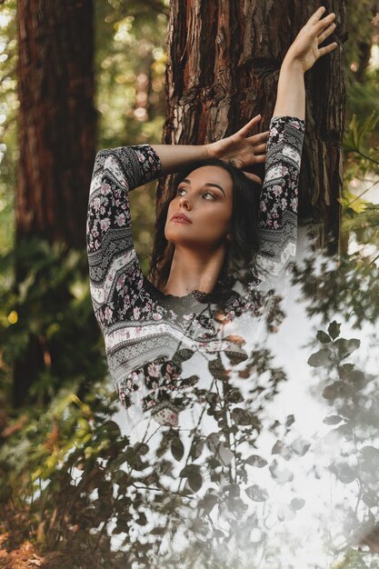 Photo woman standing by tree trunk in forest