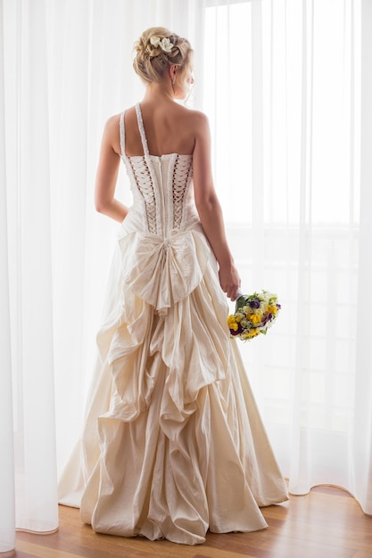 Photo woman standing by the window in her wedding dress