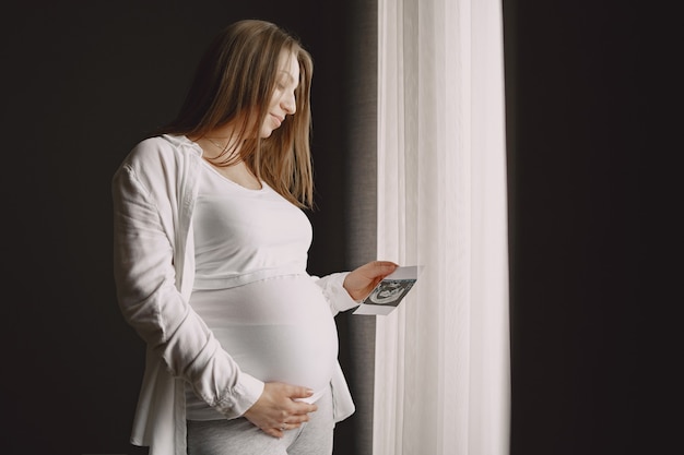 写真を見て窓際に立っている女性。