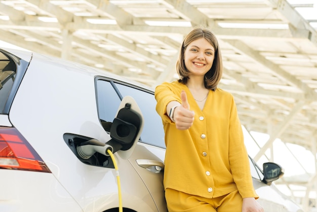 Woman standing on charging station looking at camera and showing thumb up