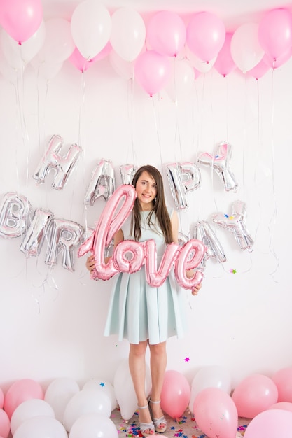 Photo woman standing in decorations with balloons and confetti for birthday party