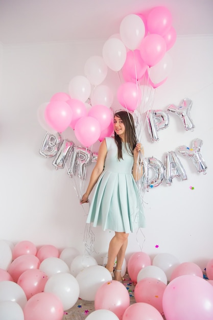 Woman standing in decorations with balloons and confetti for birthday party