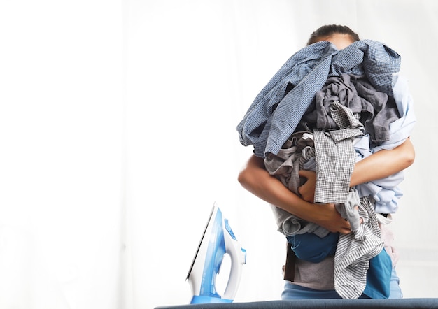 Woman standing and embracing clothes and blue electric iron