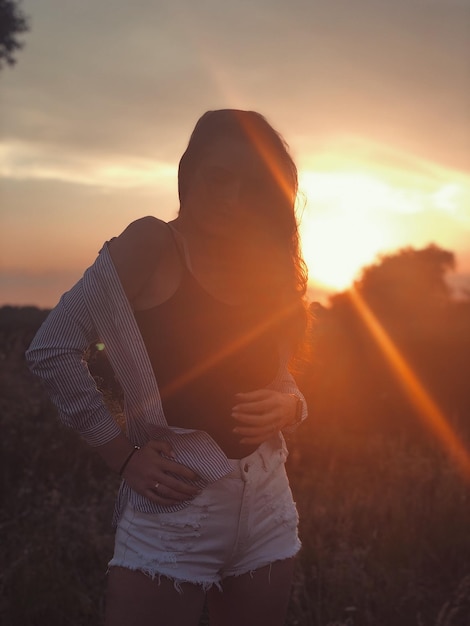 Foto donna in piedi sul campo contro il cielo durante il tramonto