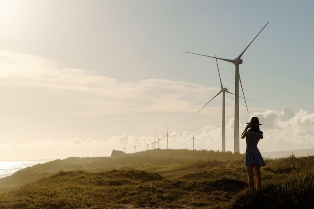 woman standing on field with wind turbines against sky