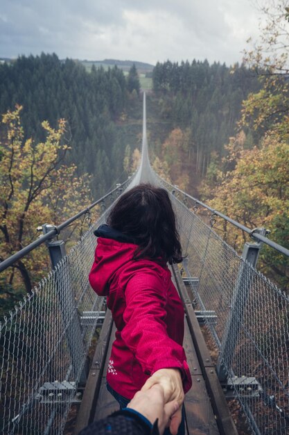 Photo woman standing on footbridge in forest