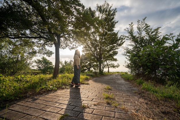 woman standing on footpath against trees