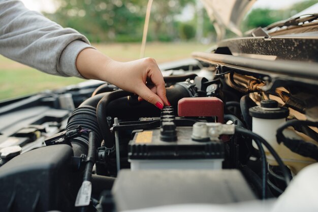 壊れた車の前に立っている女性。車の問題。問題がどこにあるのかわかりません。何が問題なのか..道路で壊れた車