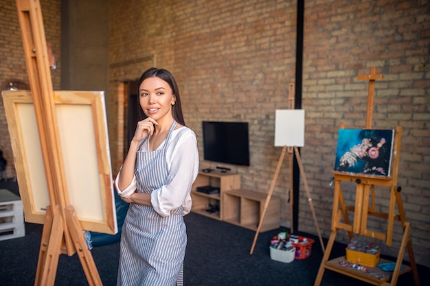 Woman standing in front of the easel while working in the art studio