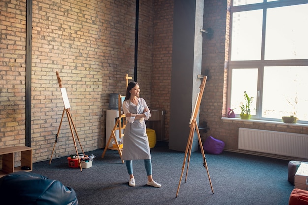 Photo woman standing in front of the easel while working in the art studio