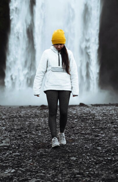 Donna in piedi di fronte alla cascata skógafoss, islanda