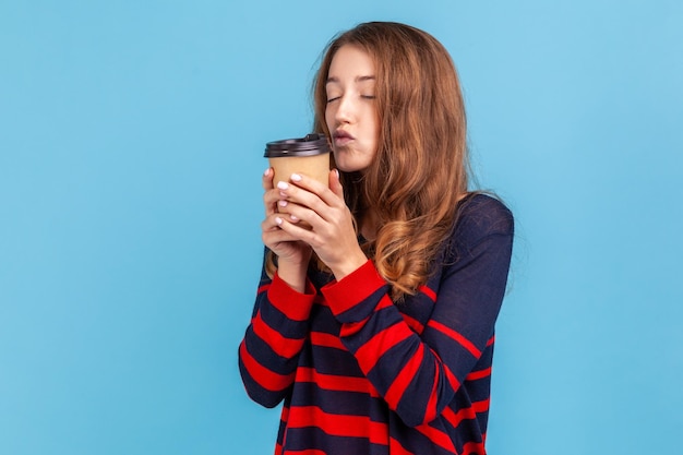 行くためにコーヒーを持って立っている女性は唇の口を保ちます熱い飲み物を飲むために幸せなエネルギーが必要です