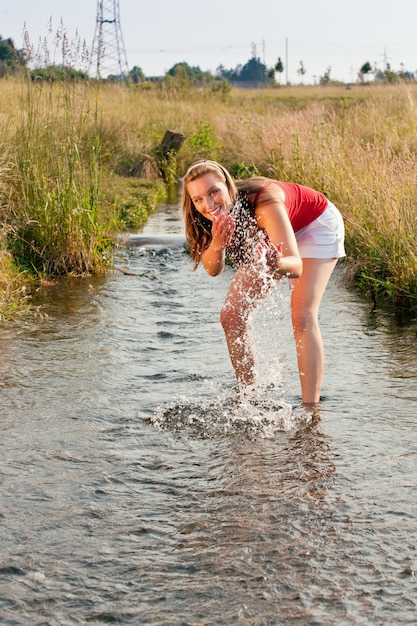 Женщина стоит в маленьком ручье с лодыжками в воде