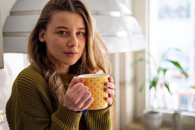 Woman standing in the kitchen and drinking cup of tea