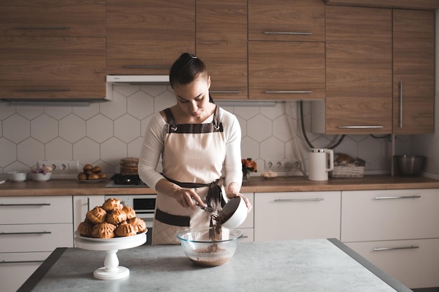 Женщина, стоящая на кухне, делая тесто для шоколадного торта