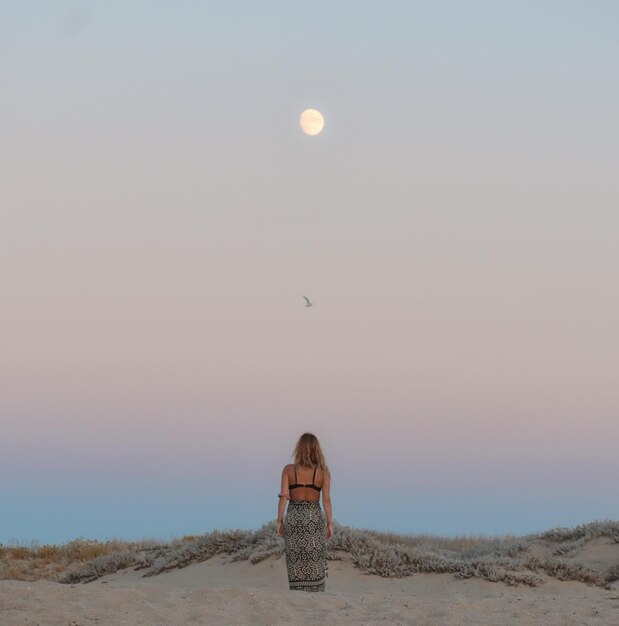 Foto donna in piedi sulla terra contro il cielo durante il tramonto