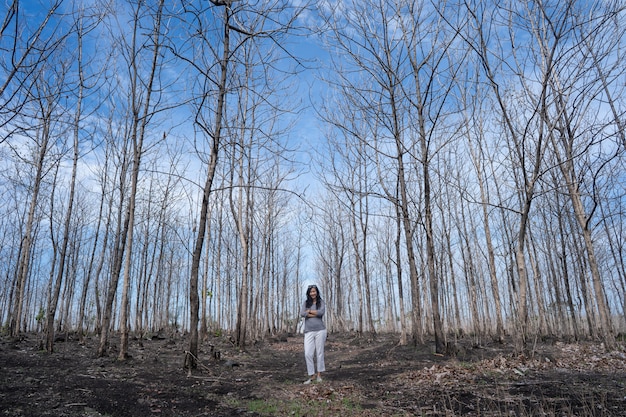 Woman standing in the middle of the wood with leafless trees