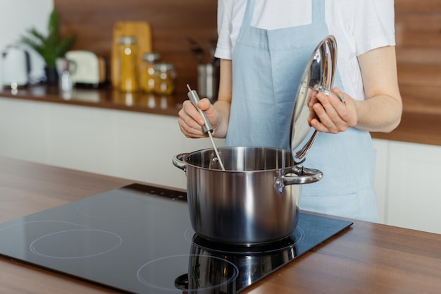 現代のキッチンで鍋で料理をしている女性