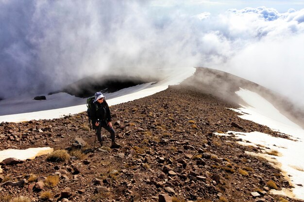 Woman standing on mountain against cloudy sky