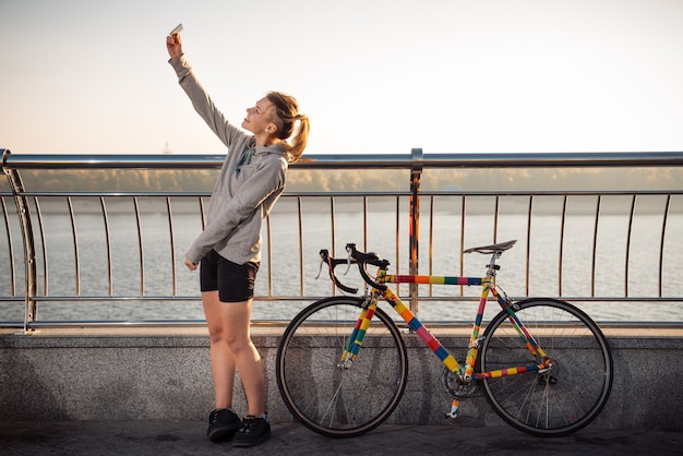 Woman standing near bicycle and making selfie