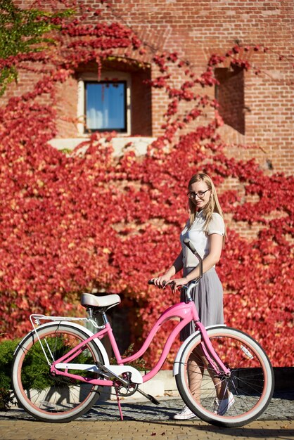 ピンクの自転車の近くに立っている女性